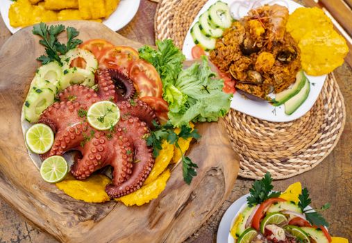 Delicious seafood platter with octopus and vegetables, presented on a rustic wooden board.