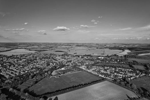 Black and white aerial view of English countryside farmland with scattered houses and fields.