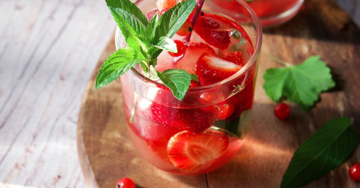 Glass of strawberry and mint drink with ice, perfect for a refreshing summer experience.