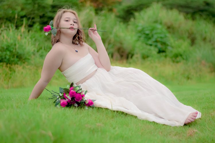 Woman Biting A Pink Rose