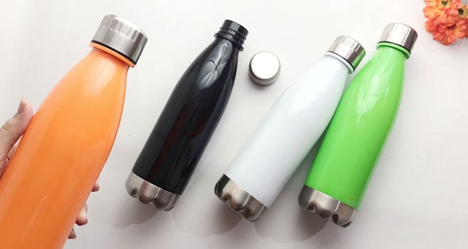 Flatlay of vibrant stainless steel water bottles in assorted colors on a white surface.