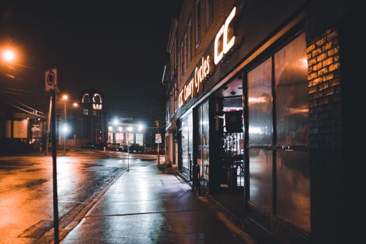 Moody urban night scene with wet sidewalks and reflections on a deserted city street.