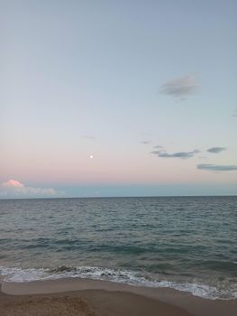 A tranquil ocean view featuring the moon and soft clouds in a pastel sky, perfect for nature lovers.