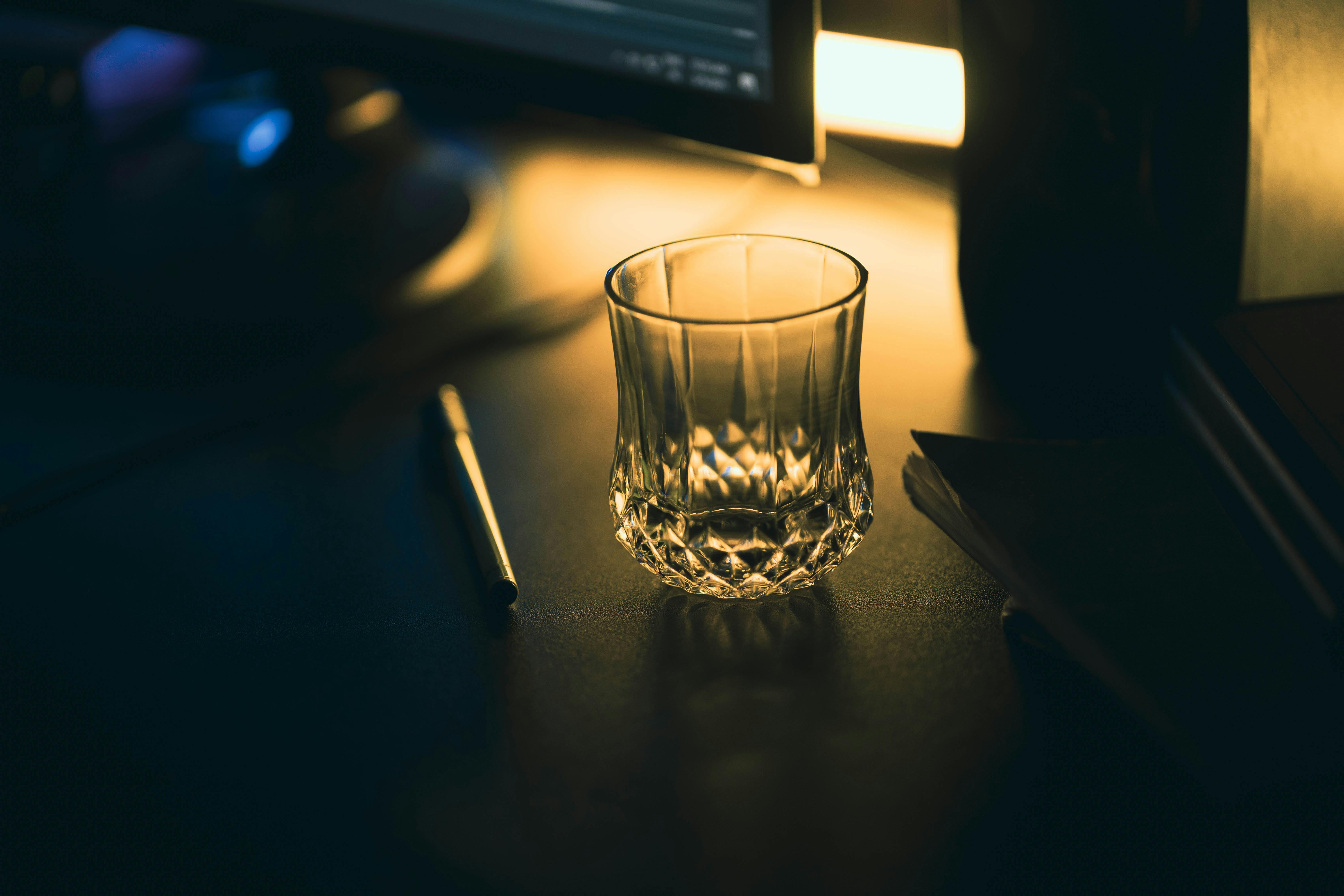 Elegant crystal glass and pen on a dark desk with warm lighting ambiance