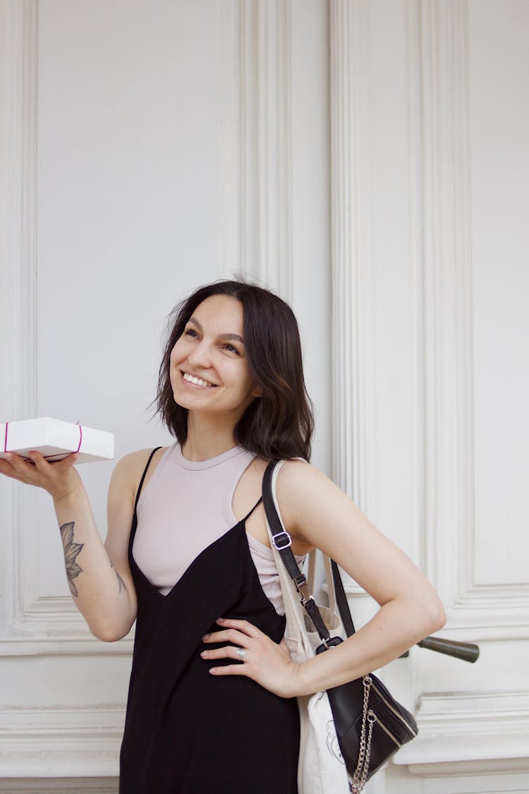 A Woman In Black Dress Looking Up While Holding A Box