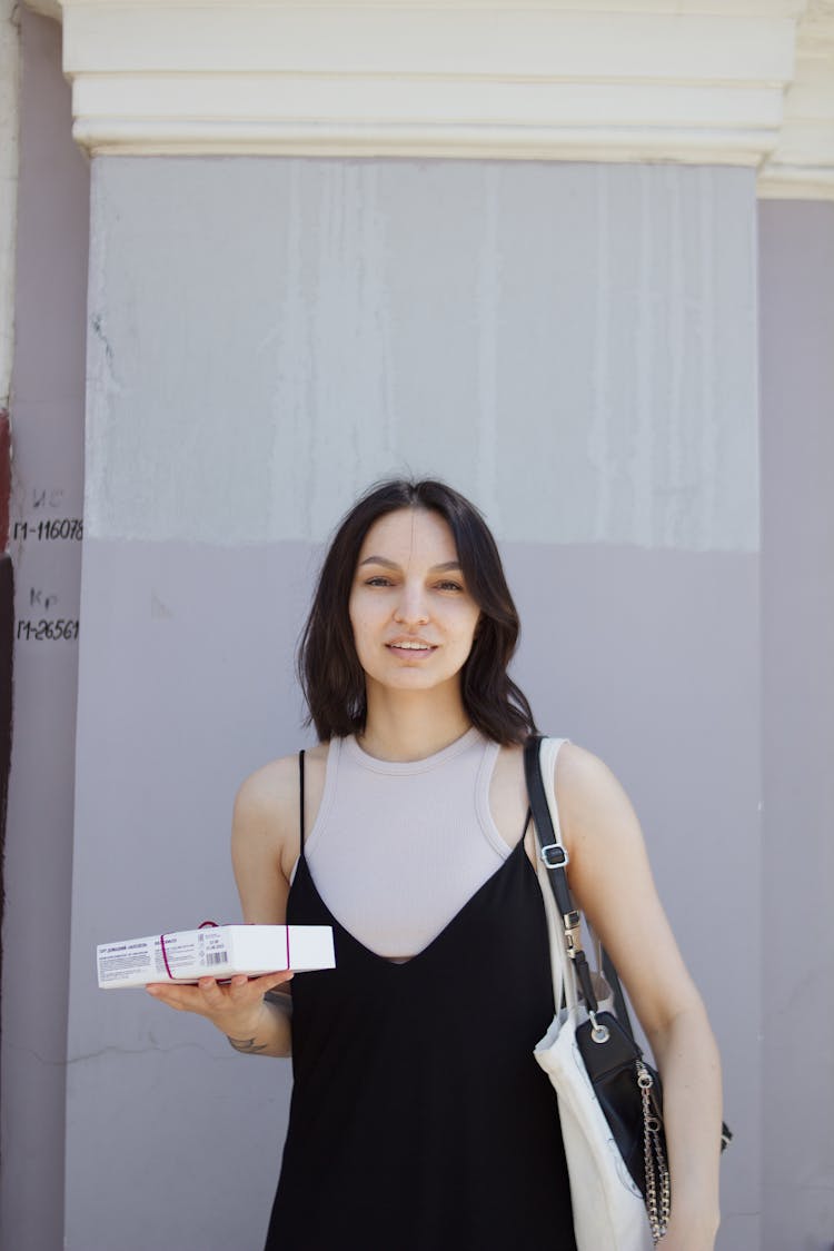 A Woman In Black Dress Holding A Box