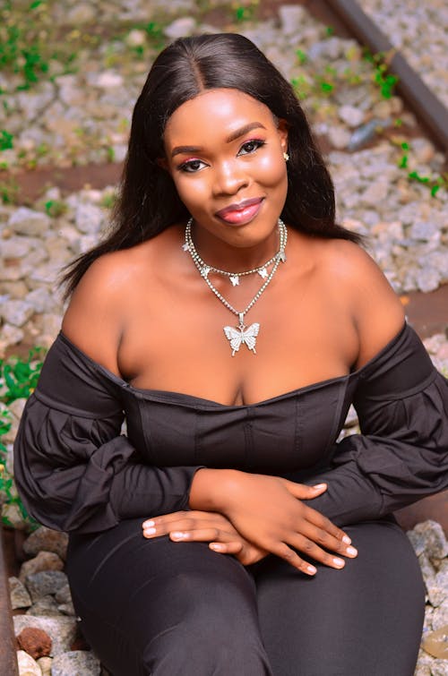 A Beautiful Woman in Black Off Shoulder Top Wearing a Silver Necklaces with Butterfly Pendant