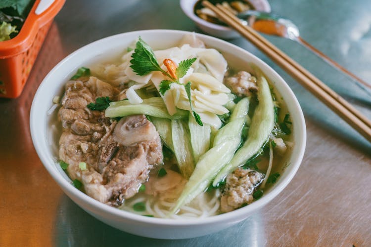 Round White Ceramic Bowl Filled With Noodles And Vegetables