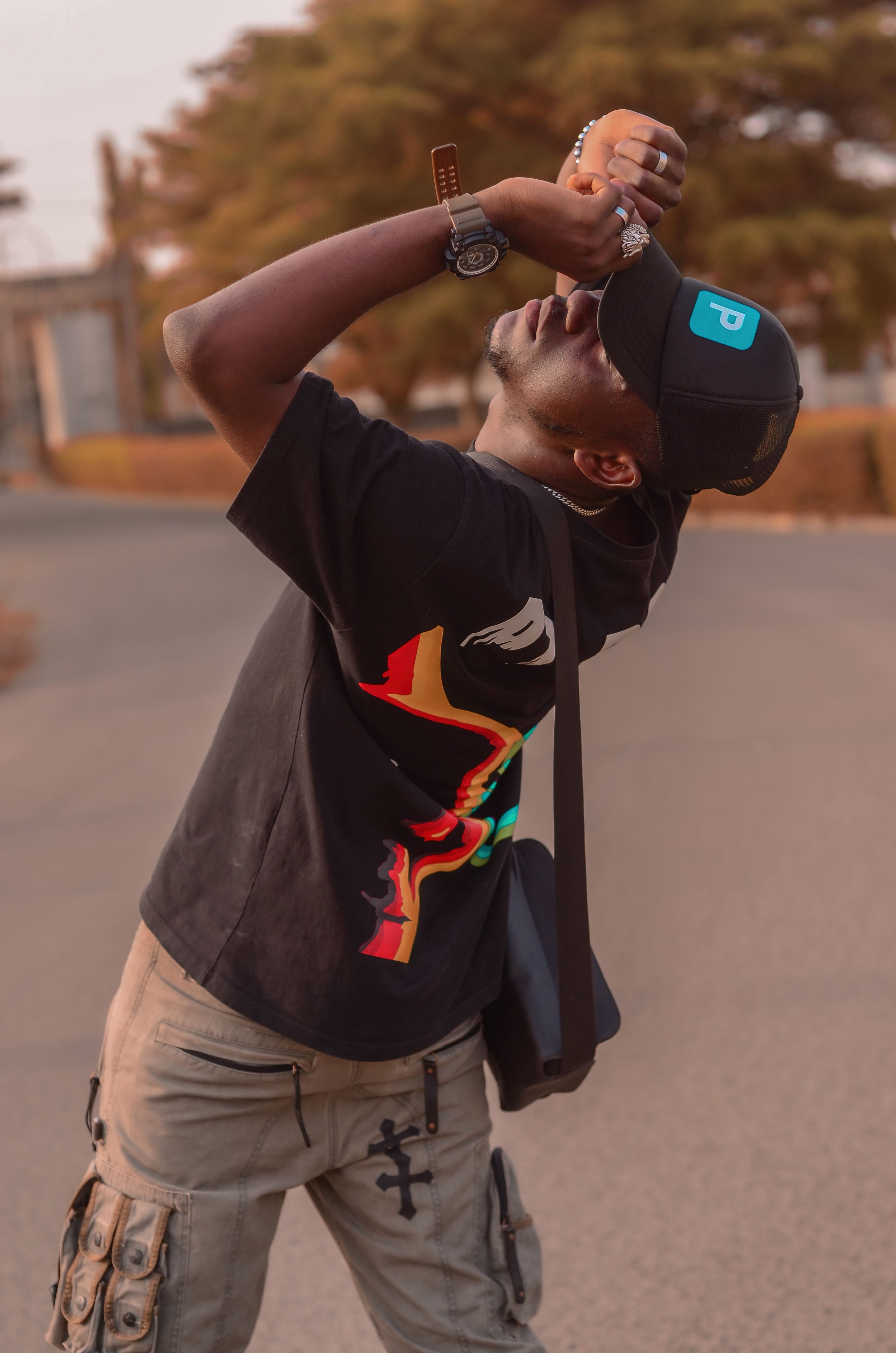 African American man posing stylishly outdoors in casual wear with artistic expression.