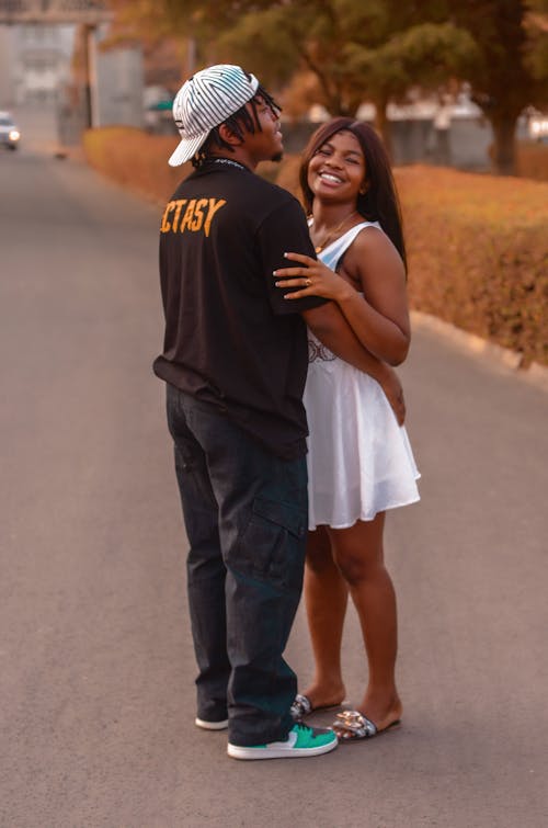 A Couple Embracing Each Other while Standing on the Street