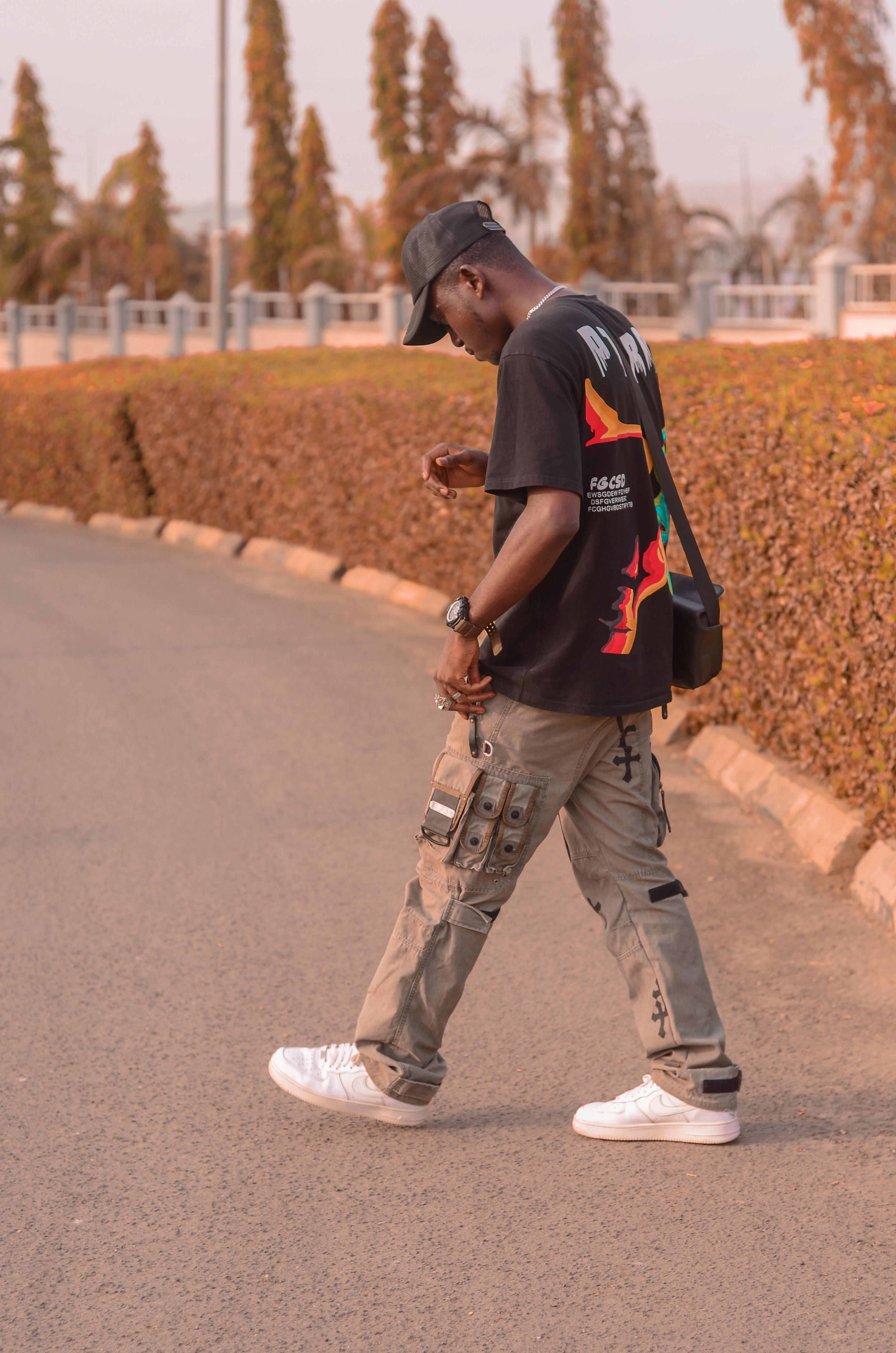 Black man walking outdoors in stylish casual wear, street fashion capture.