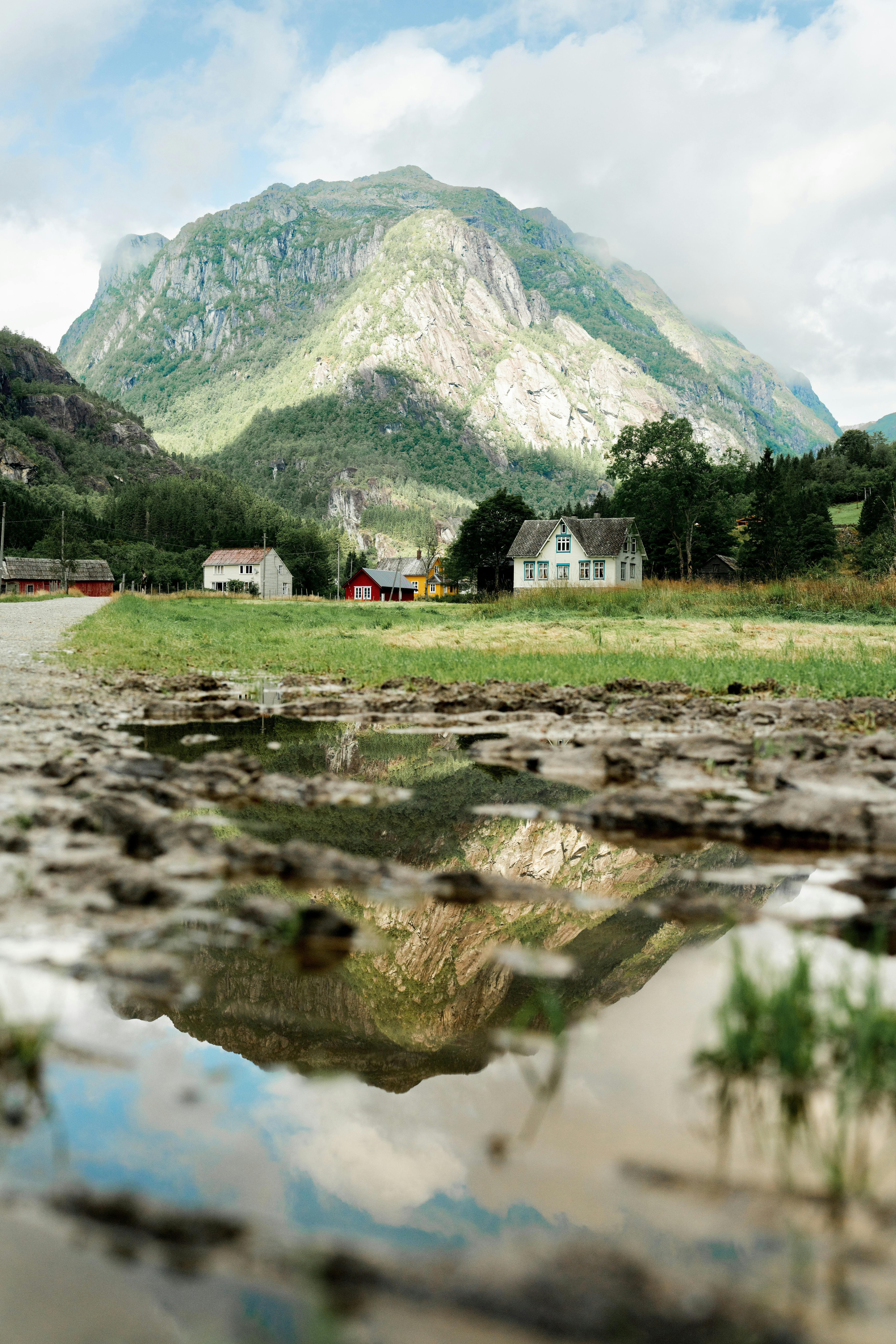 Scenic view of Vestland, Norway with picturesque mountains and rural homes reflecting in water.