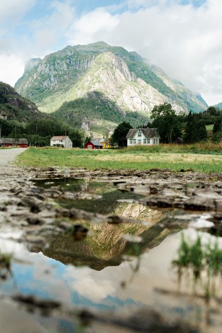 Scenic view of Vestland, Norway with picturesque mountains and rural homes reflecting in water.