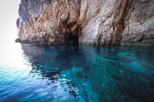 Free A breathtaking view of a rocky sea cave with clear turquoise waters, offering a serene and natural escape. Stock Photo