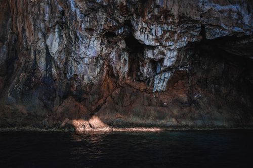 Free Sunlight reflects on the sea and rugged coastal cliff, creating a dramatic scene. Stock Photo