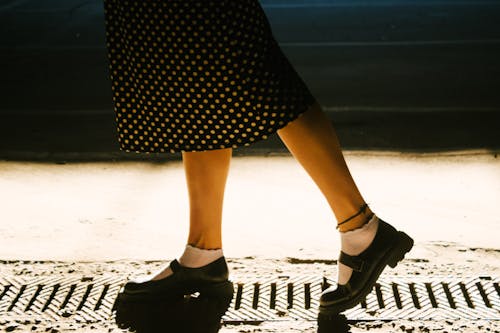 A Woman in Black and White Polka Dots Skirt and Black Leather Shoes