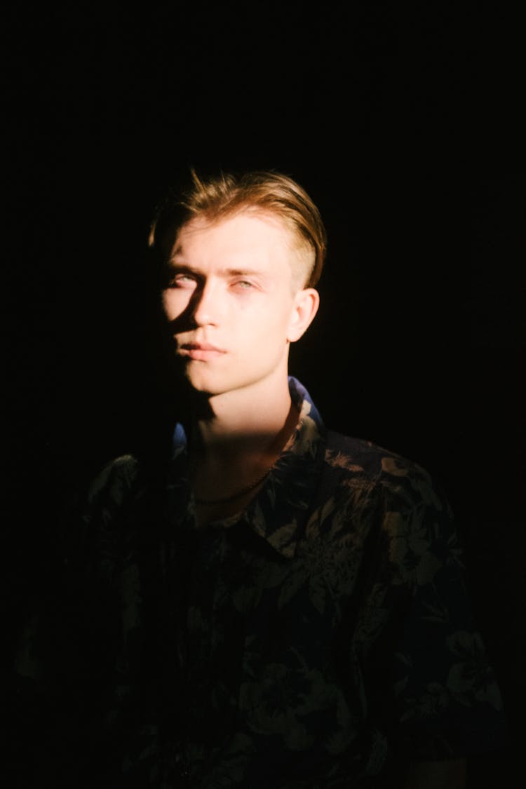 Man With Light On His Face In A Dark Room