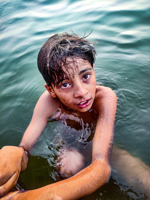 Topless Boy Swimming on Water