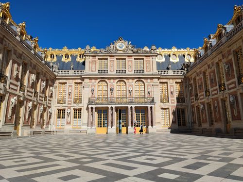 Free Stunning architectural design of the Versailles Palace marble courtyard under a clear blue sky. Stock Photo