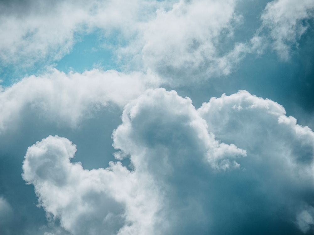 Free A peaceful cloudscape featuring soft, fluffy clouds against a clear blue sky. Stock Photo