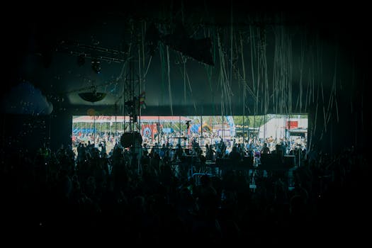 A crowd enjoying live music at a colorful outdoor festival stage.