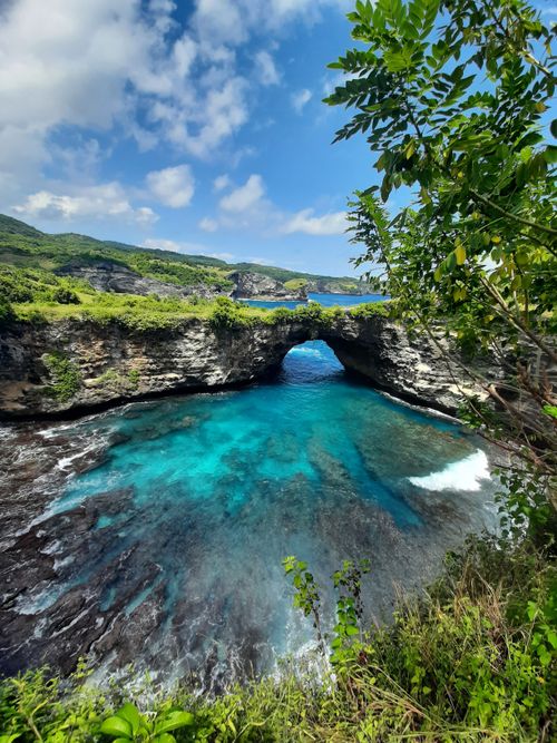 Free Explore the stunning coastal view featuring a natural rock arch and vibrant blue waters. Stock Photo