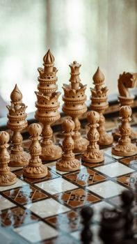 Close-up of detailed wooden chess pieces on a unique patterned board in Baku, Azerbaijan.