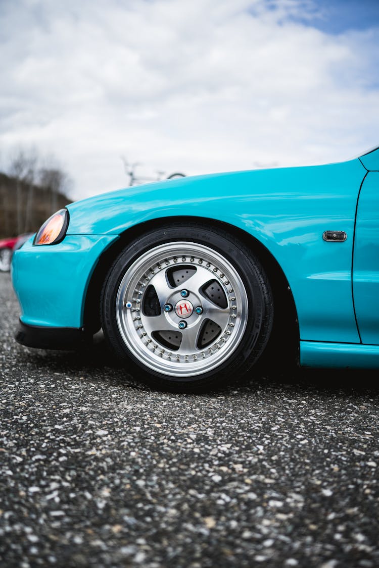 A Wheel Of A Blue Car On Gray Concrete Ground