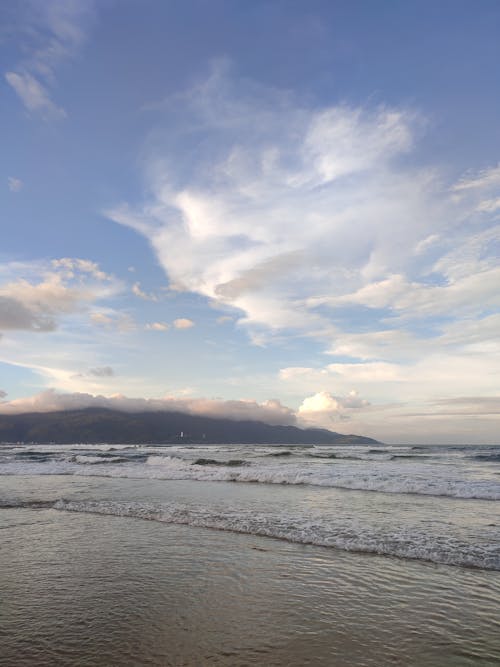 Ocean Waves Crashing on Shore Under Blue Sky