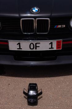Detailed vertical shot of a BMW M3 grill and toy car with license plate '1 OF 1'.