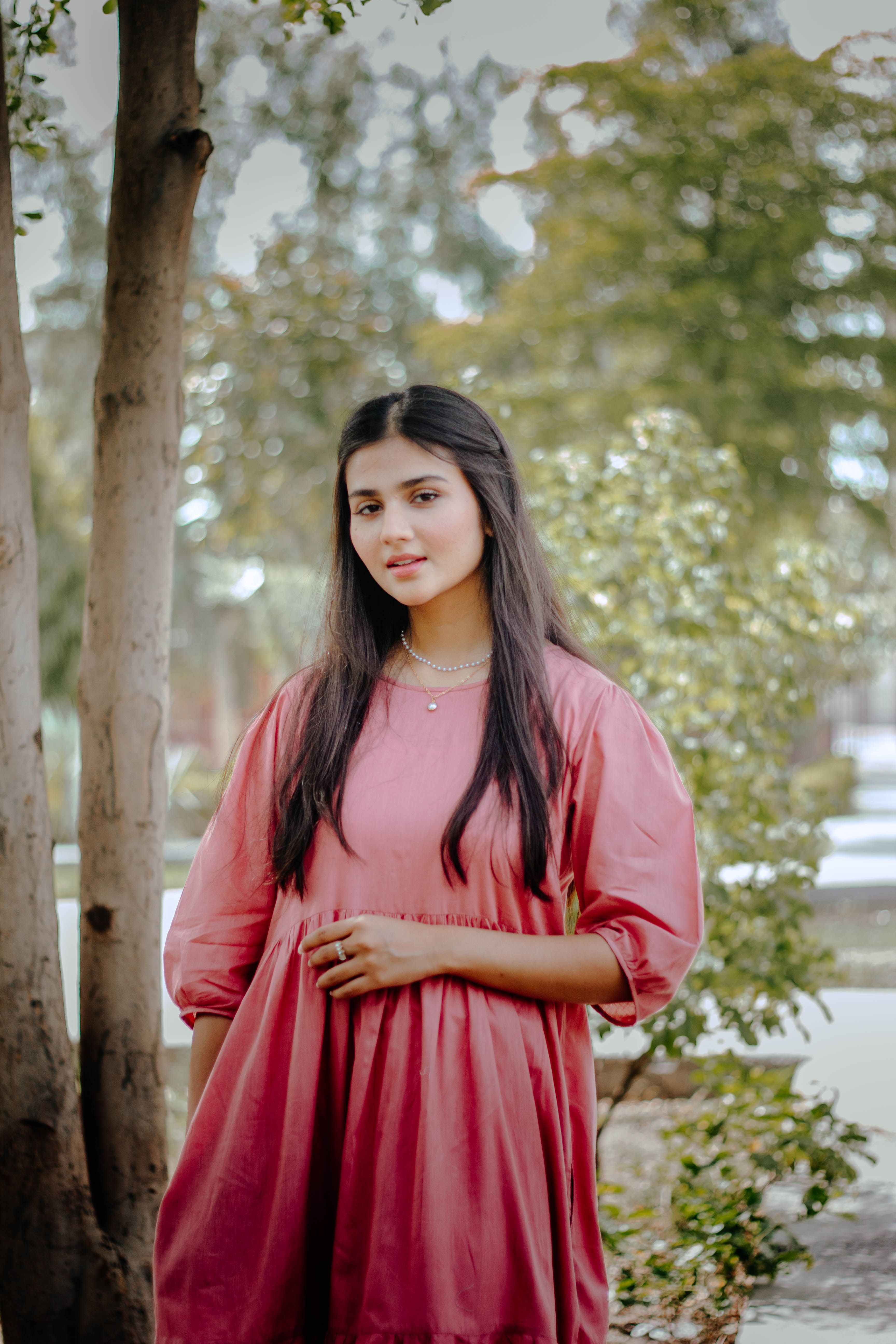 A Woman in a Pink Dress Standing Near a Tree · Free Stock Photo