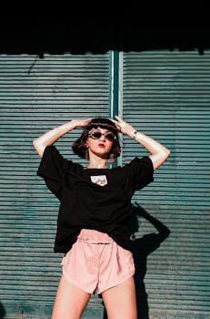 Fashionable woman in sunglasses poses confidently against a roll-up door outdoors.