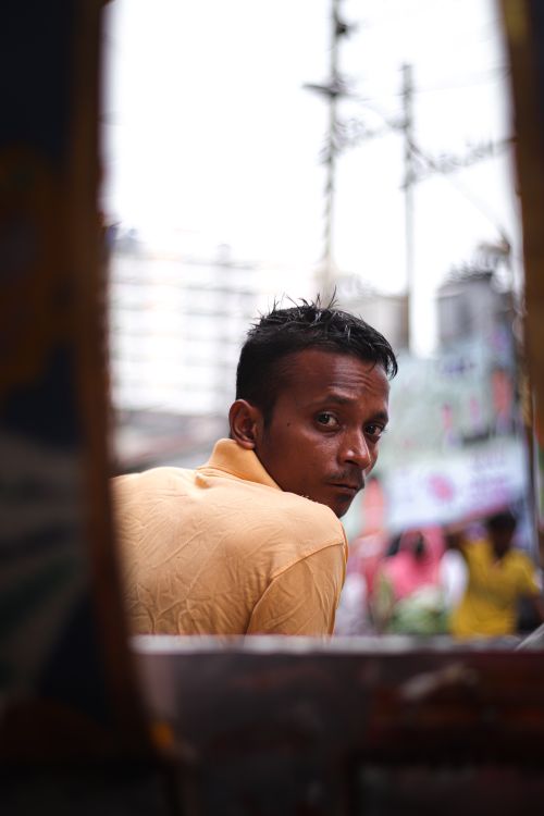 Free A man in a yellow shirt glancing over his shoulder in a busy city environment. Stock Photo
