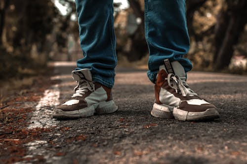 Person in Blue Denim Pants and Brown and White Sneakers
