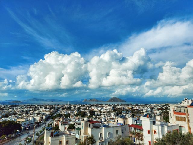 Vivid aerial view of a city's skyline by the sea with dramatic cloud formations.