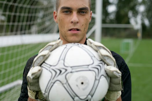 Focused soccer goalkeeper holding the ball confidently on the field.