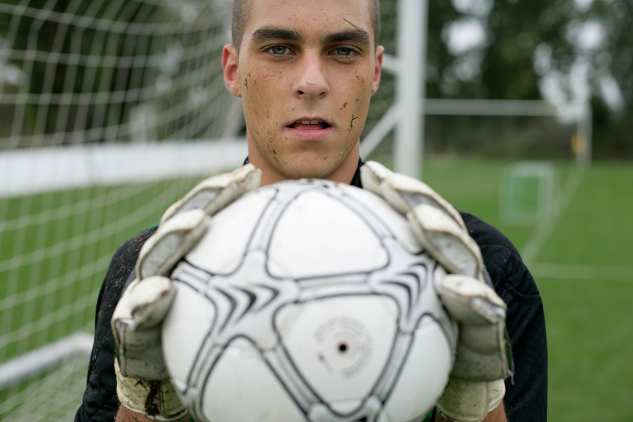 focused soccer goalkeeper holding the ball confidently on the field
