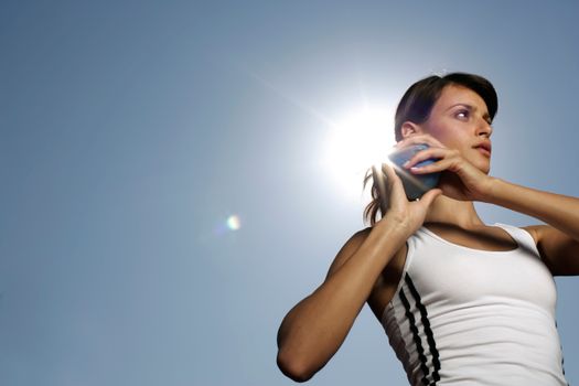 Focused female athlete in sportswear ready for shot put against clear blue sky.