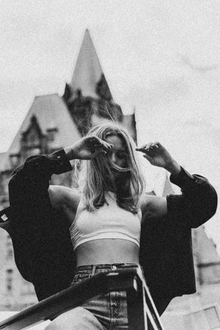 Stylish woman in crop top and denim against historic Ottawa architecture in artistic monochrome shot.