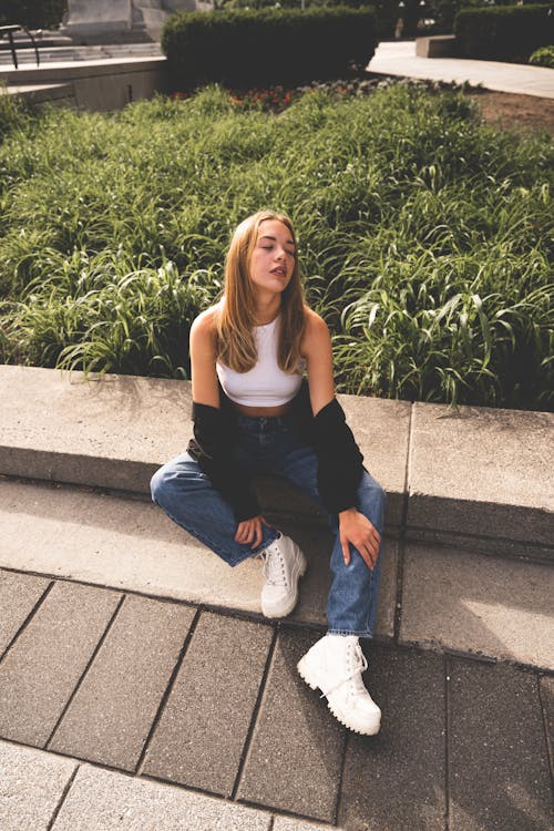 Woman in White Crop Top Sitting on Concrete Bench 