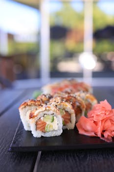 Tantalizing close-up of fresh salmon uramaki with pickled ginger on a black platter.