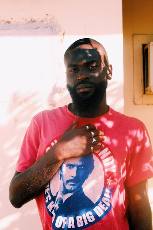 A Bearded Man in Pink Shirt Wearing Silver Rings with His Hand on His Chest