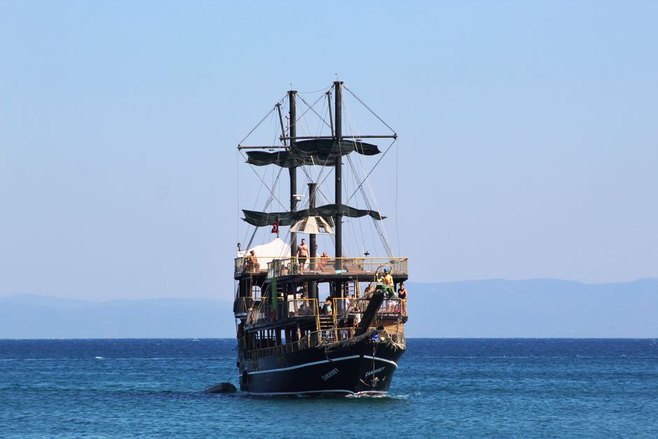 Vintage pirate ship sailing on the turquoise ocean under a clear blue sky.