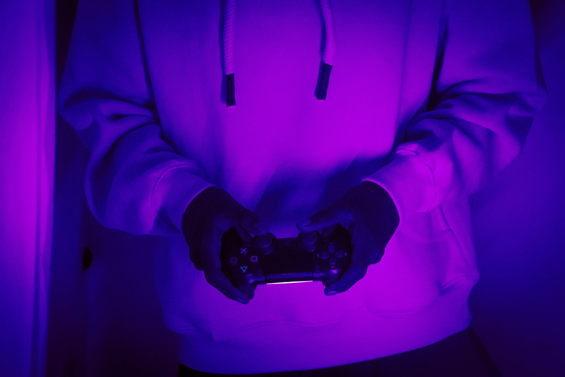 Gamer holding a controller under neon purple light