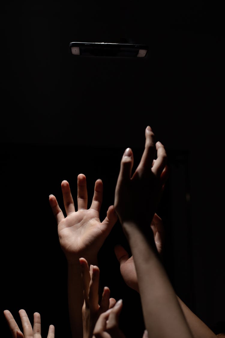 Studio Shot Of Hands Reaching On Black Background