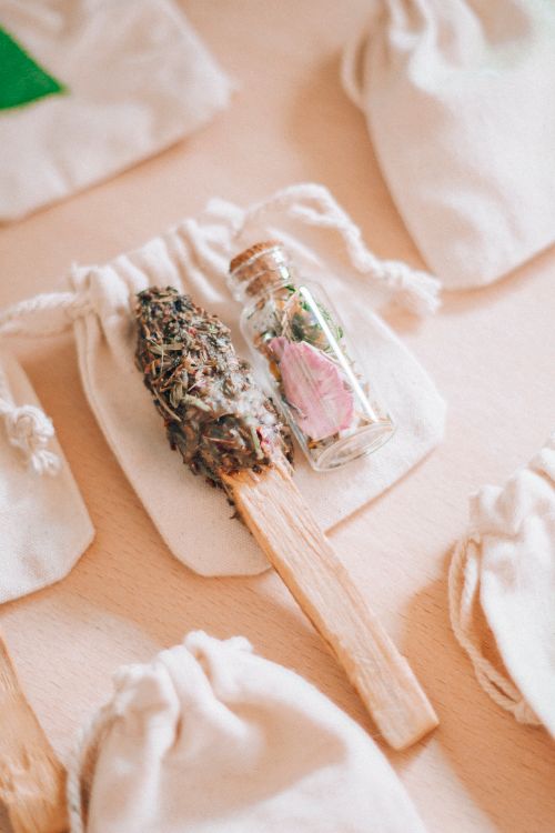 Free Aromatherapy setup featuring a palo santo stick, sage bundle, and a bottle with herbs and flowers on a fabric sack. Stock Photo