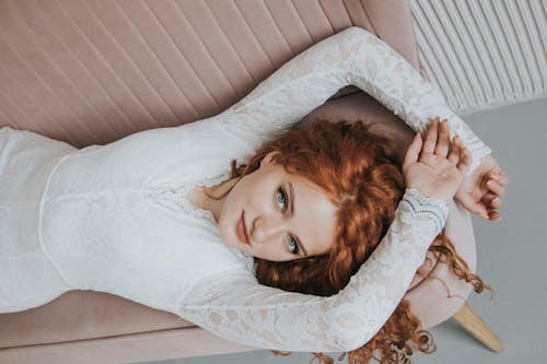 Free Woman in White Long Sleeve Shirt Lying on a Sofa Stock Photo