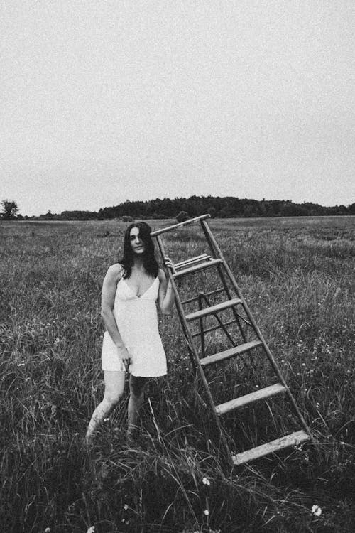 Model in Mini Dress Posing with a Ladder in a Meadow