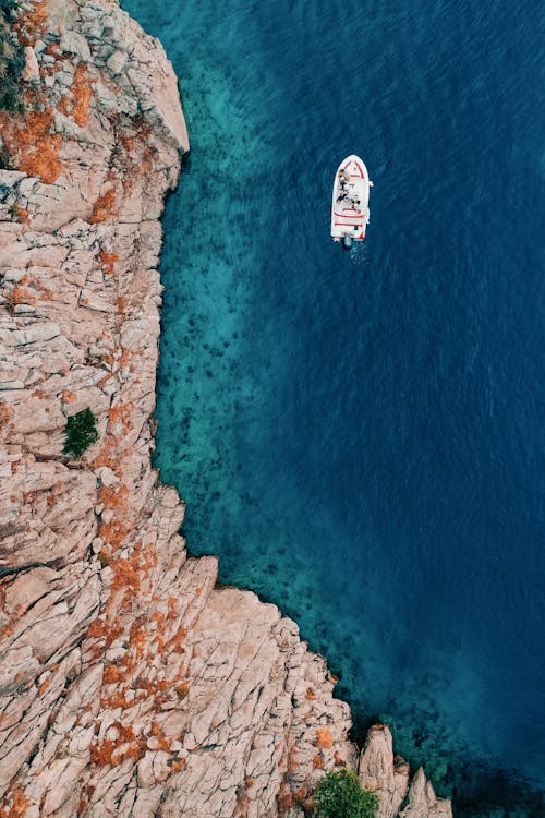 Drone Shot of Coastal Cliffs, a Boat and Blue Water