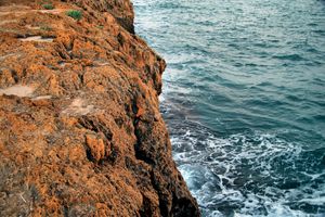 Rust-coloured cliff meeting the sea — Mario Tabarra on Pexels